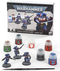 Imagem do set de Warhammer 40K com três Space Marines azuis e seis potes de tinta